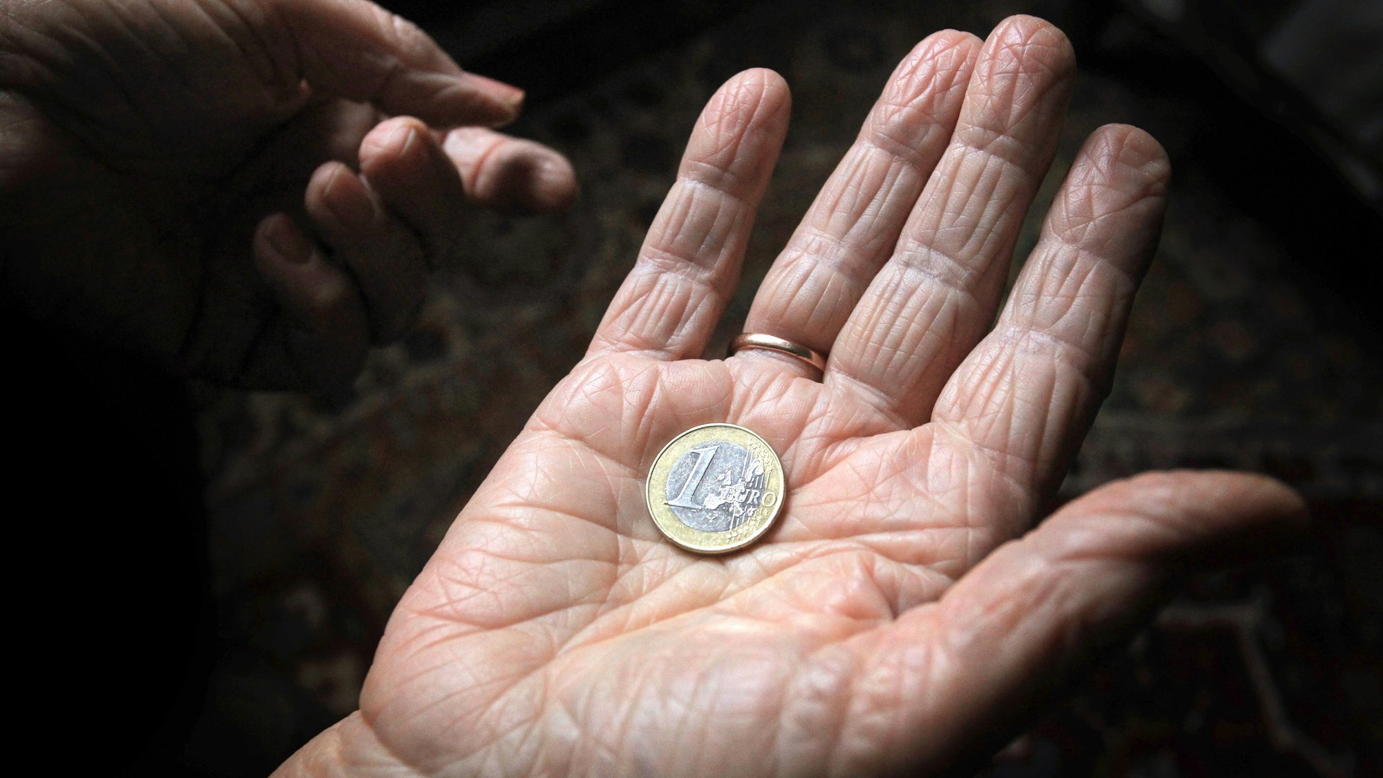 Eine 83-jährige Frau hält eine Euromünze. (Symbolbild)