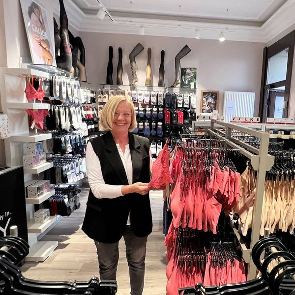 Eine Frau steht inmitten ihres Lingerie-Geschäftes.
