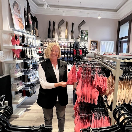 Eine Frau steht inmitten ihres Lingerie-Geschäftes.