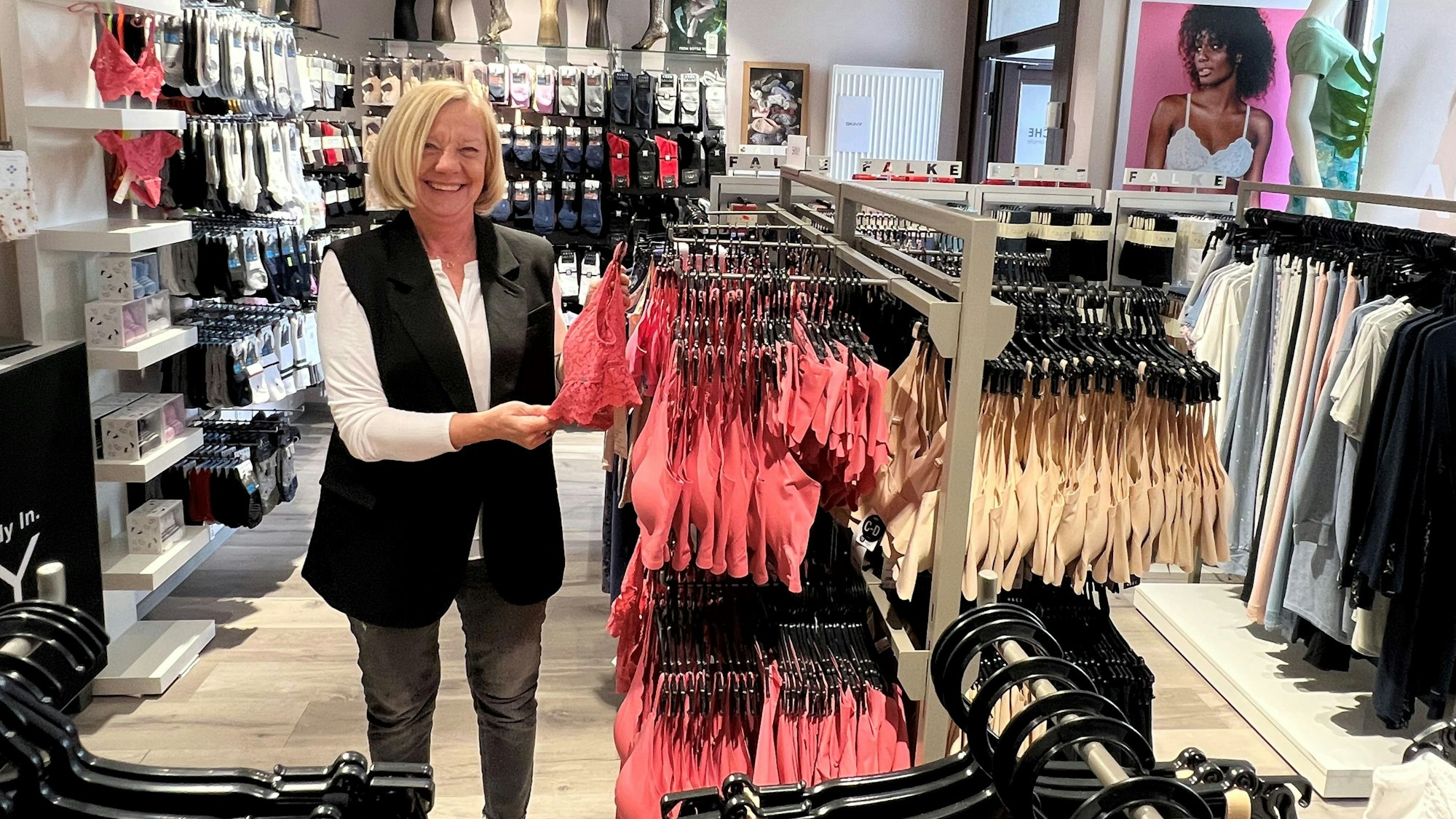 Eine Frau steht inmitten ihres Lingerie-Geschäftes.