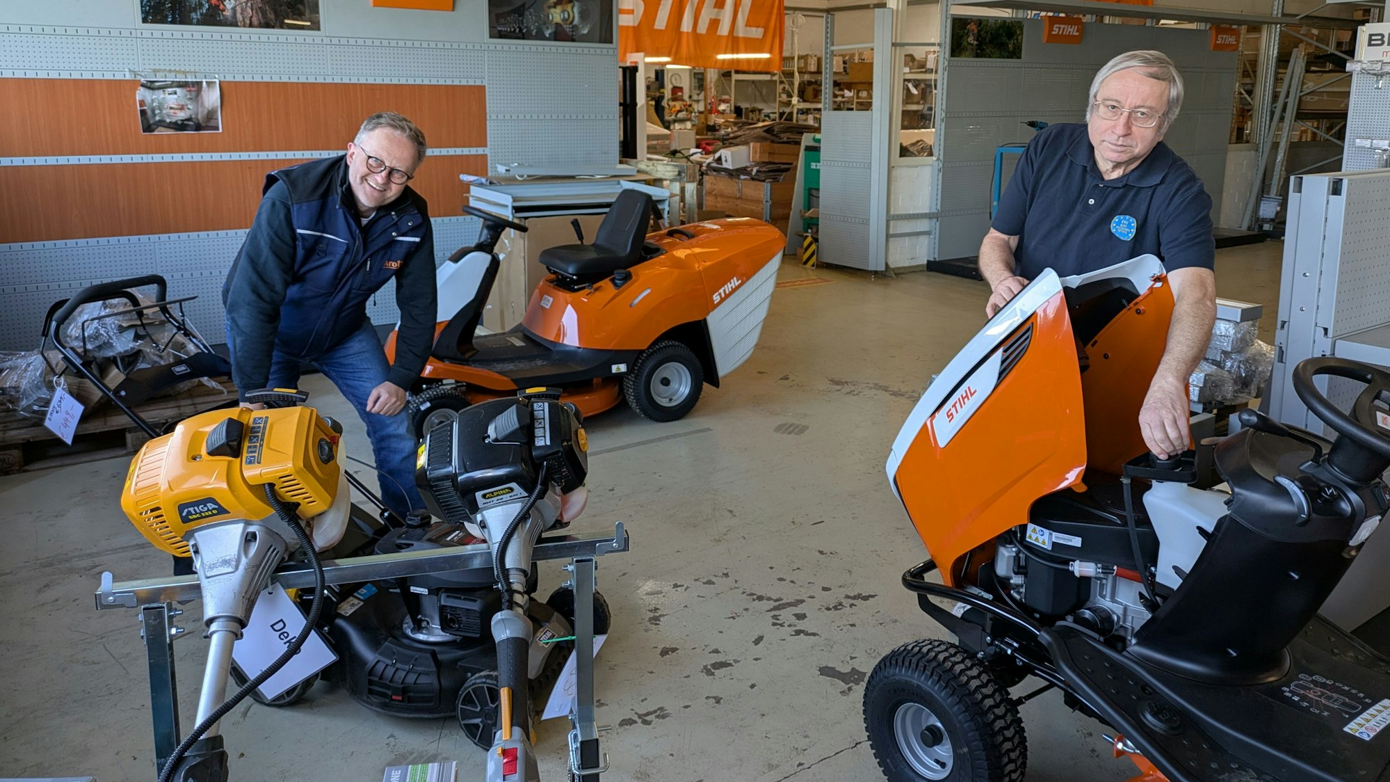 Zwei Männer bauen in einem Verkaufsraum Gartengeräte auf.