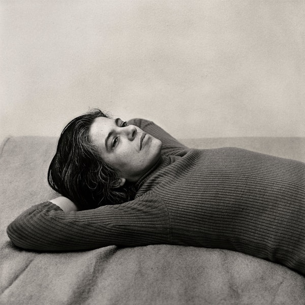 Susan Sontag hat sich in dieser Schwarz-Weiß-Fotografie auf einer Decke ausgestreckt und die Arme hinter dem Kopf verschränkt.
