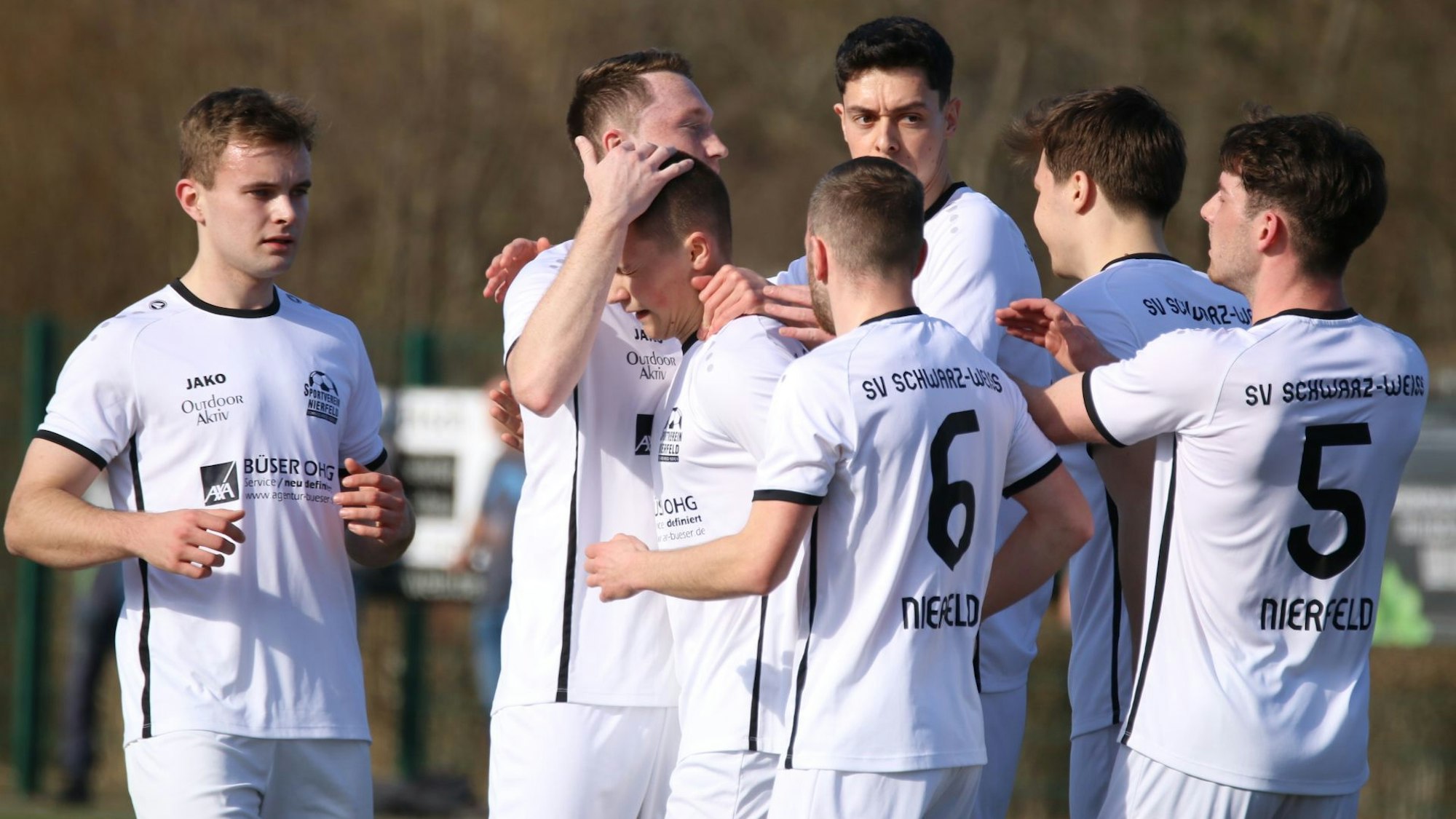 Spieler des SV Nierfeld feiern einen Torerfolg. Sie tragen weiße Trikots und weiße Hosen.