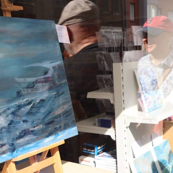 Ein Bild in einem Schaufenster, darin spiegeln sich einige Betrachter der Kunstmeile.