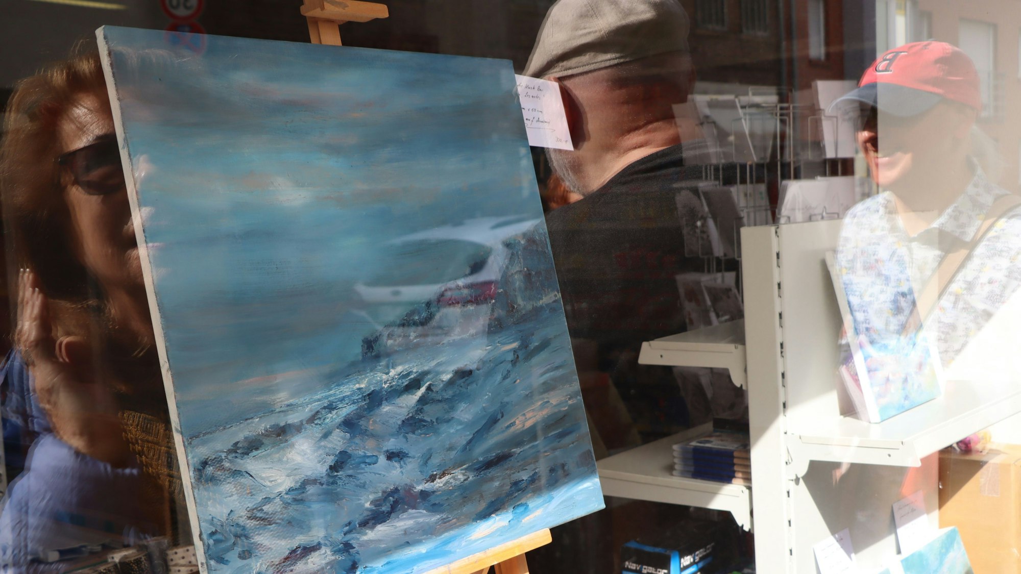 Ein Bild in einem Schaufenster, darin spiegeln sich einige Betrachter der Kunstmeile.