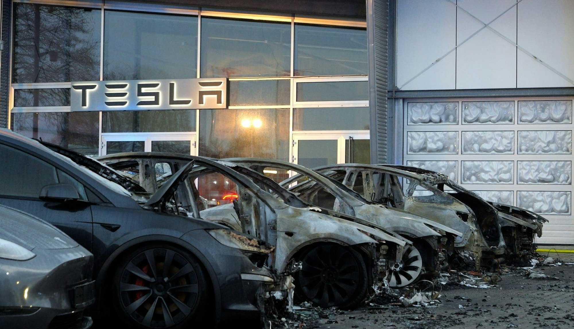 29.03.2025, Niedersachsen, Ottersberg: Ausgebrannte Elektroautos sind vor einem Tesla Autohaus zu sehen. Mehrere Elektroautos haben in Ottersberg (Landkreis Verden) gebrannt. Dabei waren die Fahrzeuge am frühen Morgen vor einem Autohaus von Tesla in Flammen aufgefangen, wie ein Sprecher der Feuerwehr mitteilte. Die Hintergründe sind aktuell unklar. Foto: Jörn Hüneke/dpa +++ dpa-Bildfunk +++