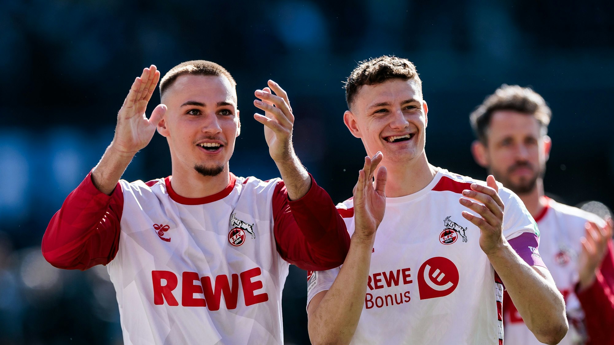 Tim Lemperle und Eric Martel applaudieren lachend Richtung Fans.