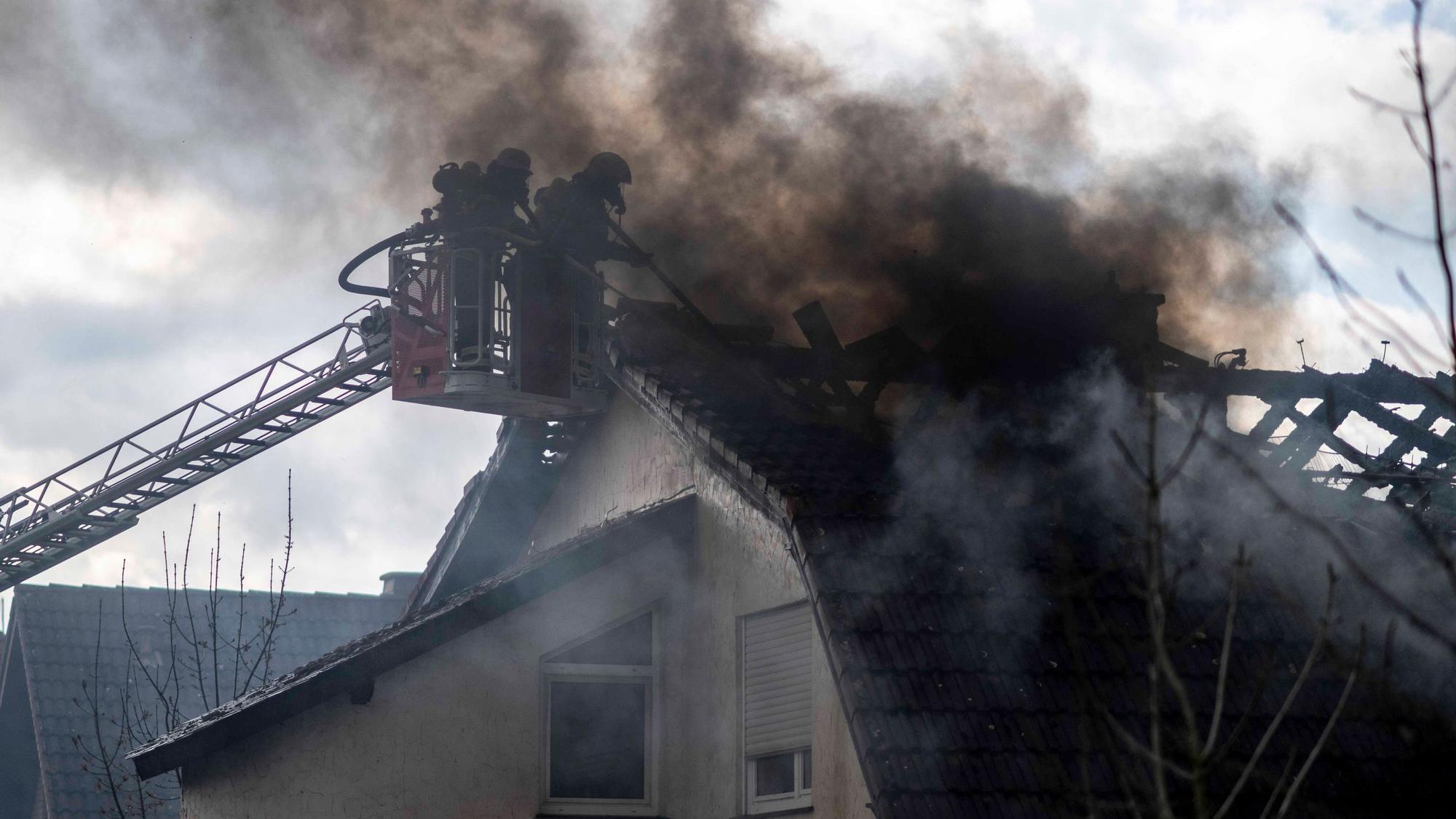 Das Bild zeigt zwei Feuerwehrleute im Korb einer Drehleiter. Sie bekämpfen im dichten Rauch einen Dachstuhlbrand.