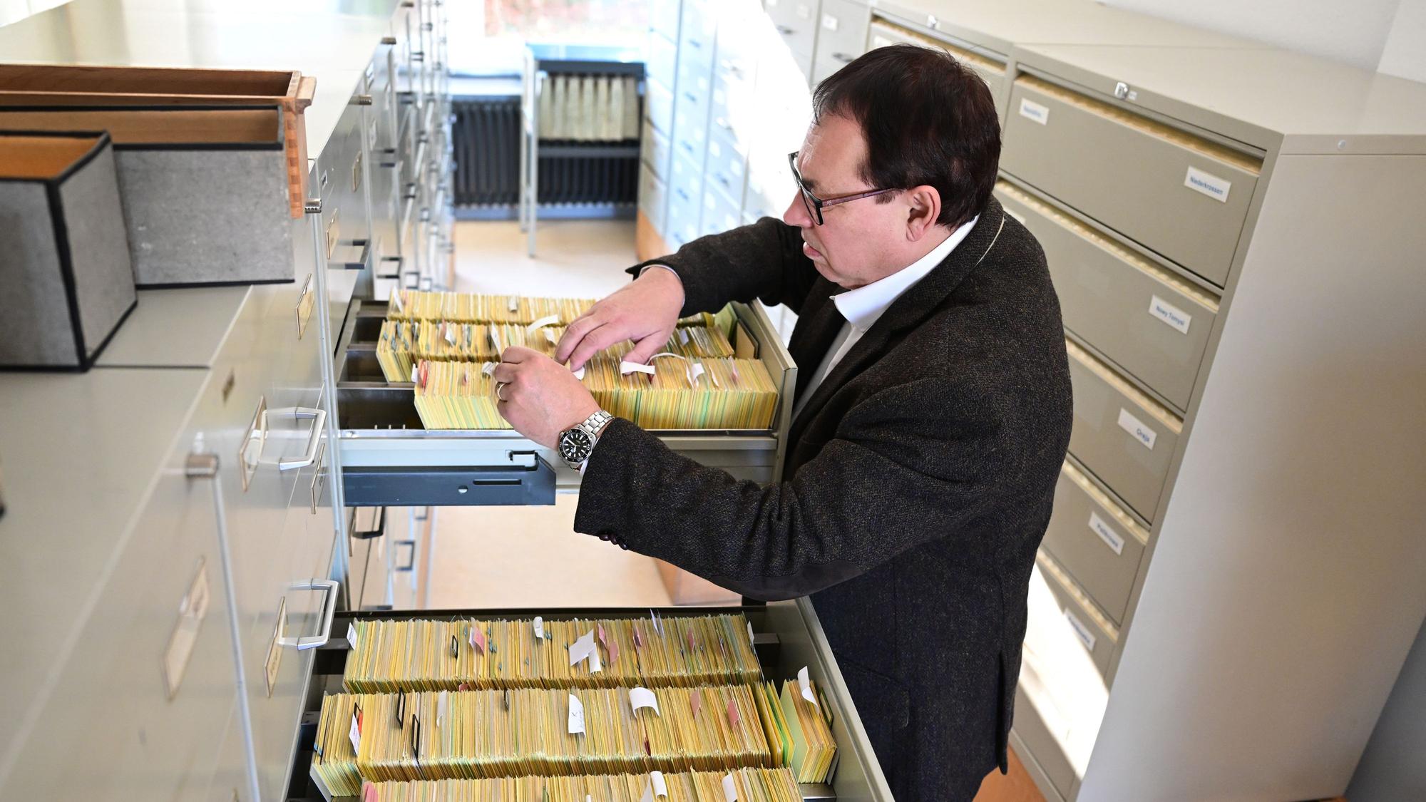 Thomas Will, Oberstaatsanwalt und Leiter der Zentralen Stelle zur Aufklärung von nationalsozialistischen Verbrechen, steht im Archiv der Einrichtung an Archivschränken mit Karteikarten.