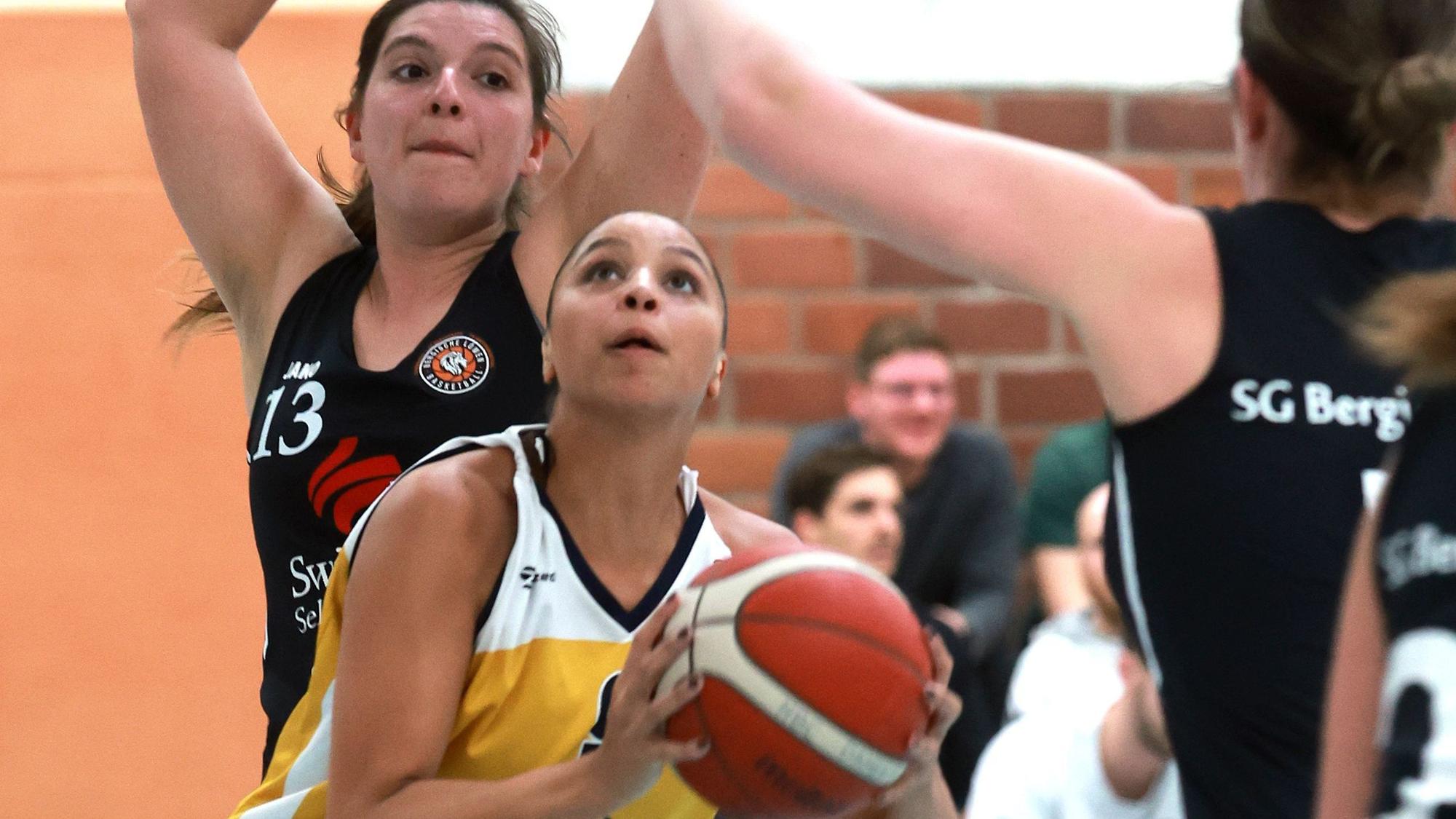 Das Foto zeigt eine Basketballerin im gelben Trikot des Hürther BC, die den Korb anvisiert.