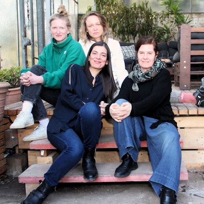 Vier Frauen sitzen auf einer Holz-Terasse.