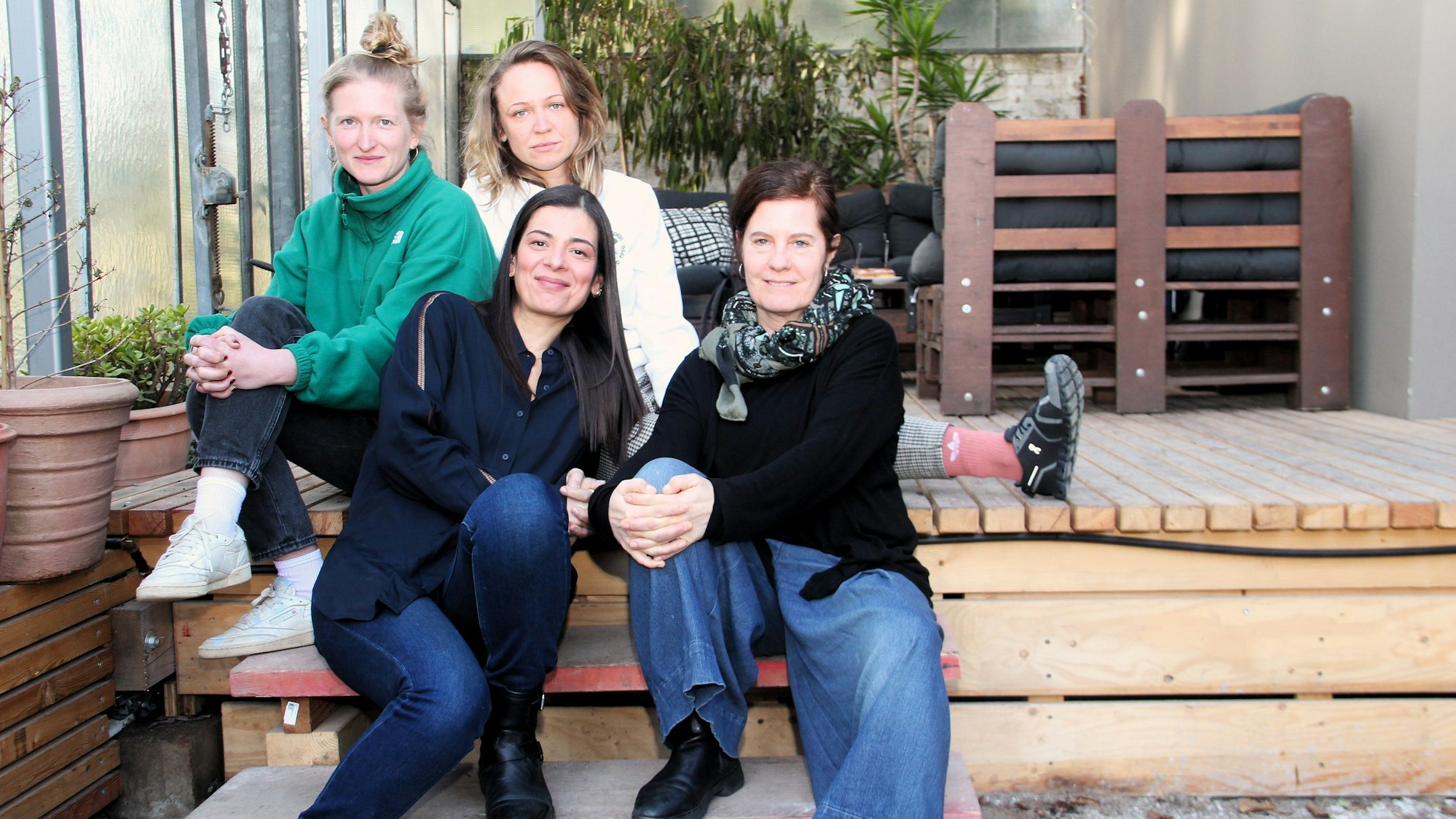 Vier Frauen sitzen auf einer Holz-Terasse.