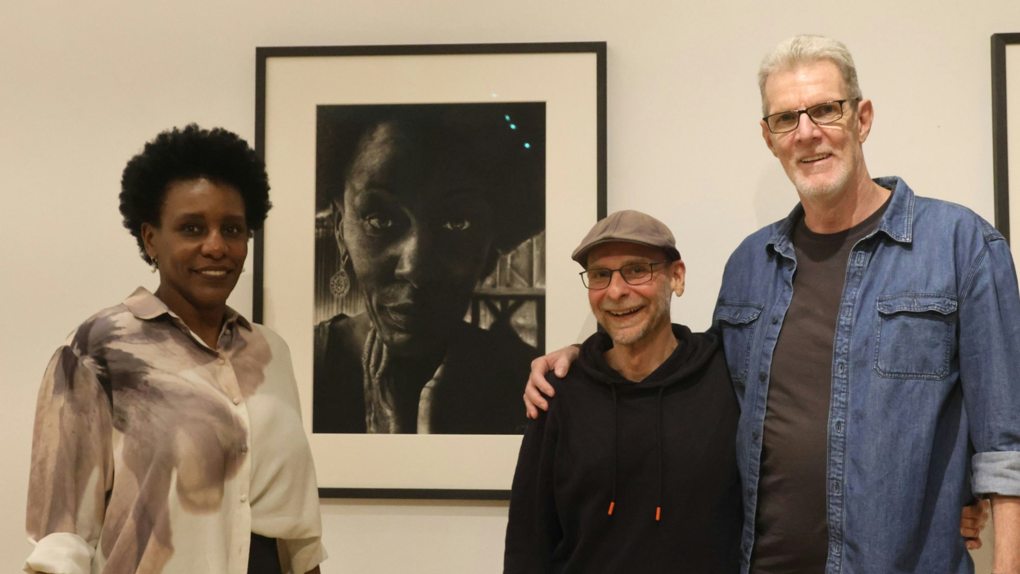 Eine Frau und zwei Männer vor einem Bild.