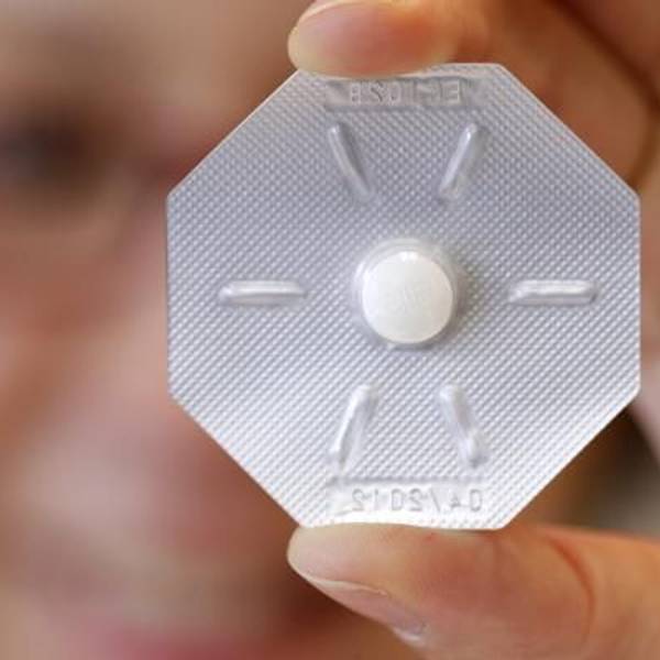Eine Frau hält ein Tabletten-Blister mit der „Pille danach“ vor ihr Auge.