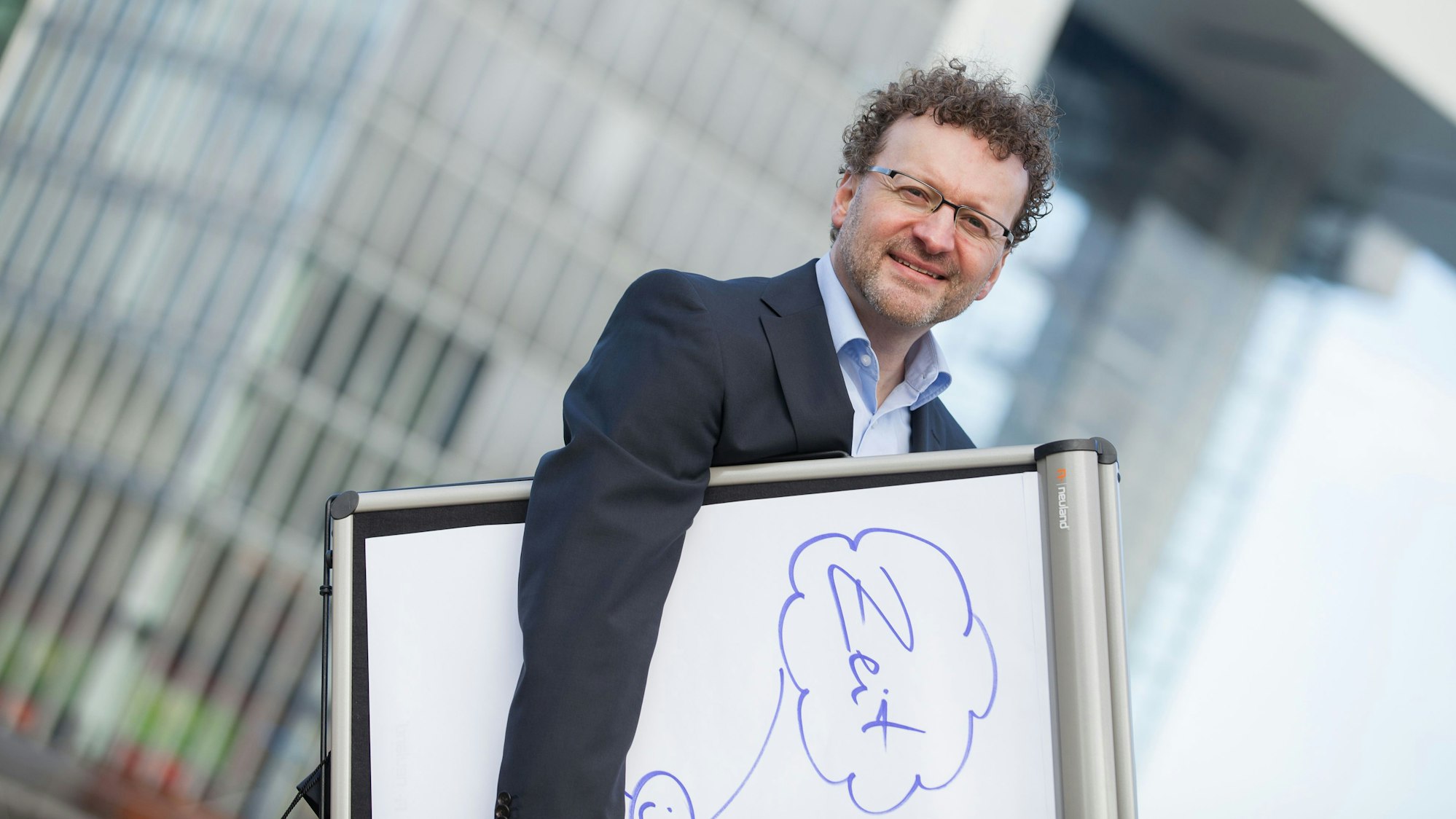 Zeitmanagement-Coach Markus Dörr trägt ein Whiteboard mit der Aufschrift „Zeit“.