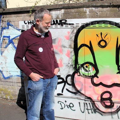 Ein Mann schaut auf ein Graffiti auf einem Stromkasten.