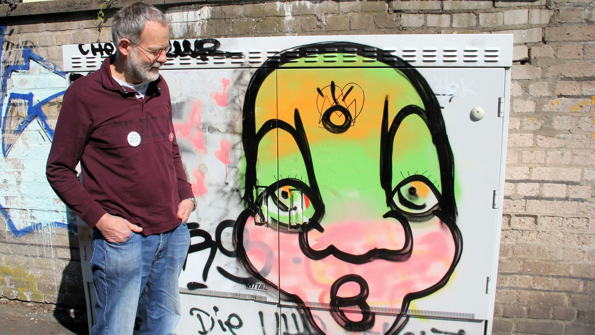 Ein Mann schaut auf ein Graffiti auf einem Stromkasten.