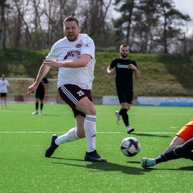 Das Bild zeigt Stefan Rempel, der den Ball gerade geschossen hat. Torhüter Jona Lorbach wirft sich ihm entgegen.