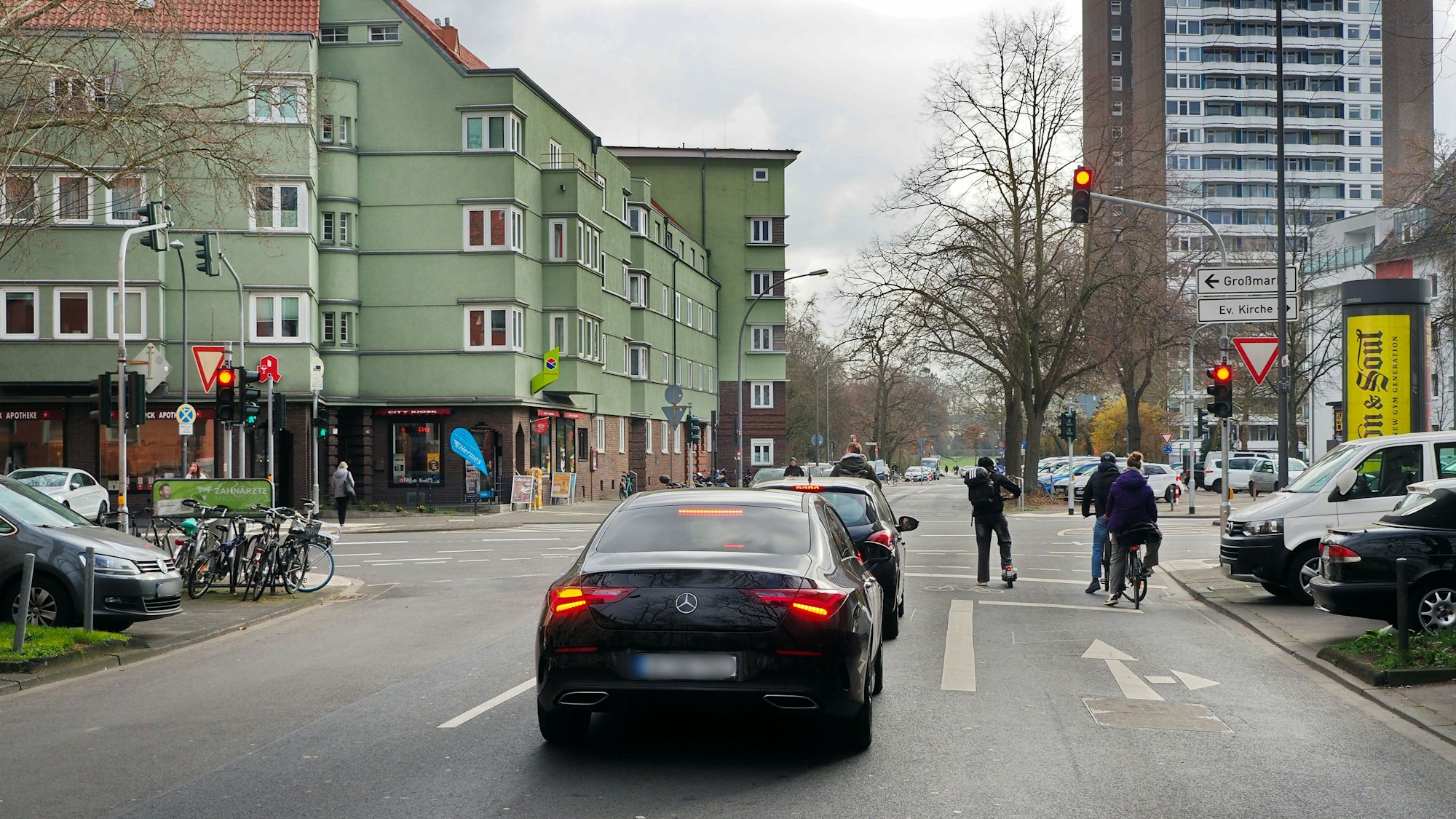 Autos und Radfahrer warten an einer Ampel-Kreuzung.