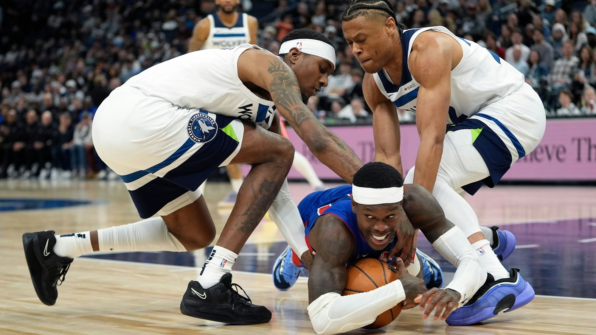 Detroit Pistons-Guard Dennis Schröder (17), fällt, während Minnesota Timberwolves-Forward Jaden McDaniels (3, l), und Guard Jaylen Clark (22, r), um den Ballbesitz kämpfen. Die Prügelei, an der Mannschaftskollegen beteiligt waren, verfolgte er stehend vor der Bank, hin und wieder applaudierte er.