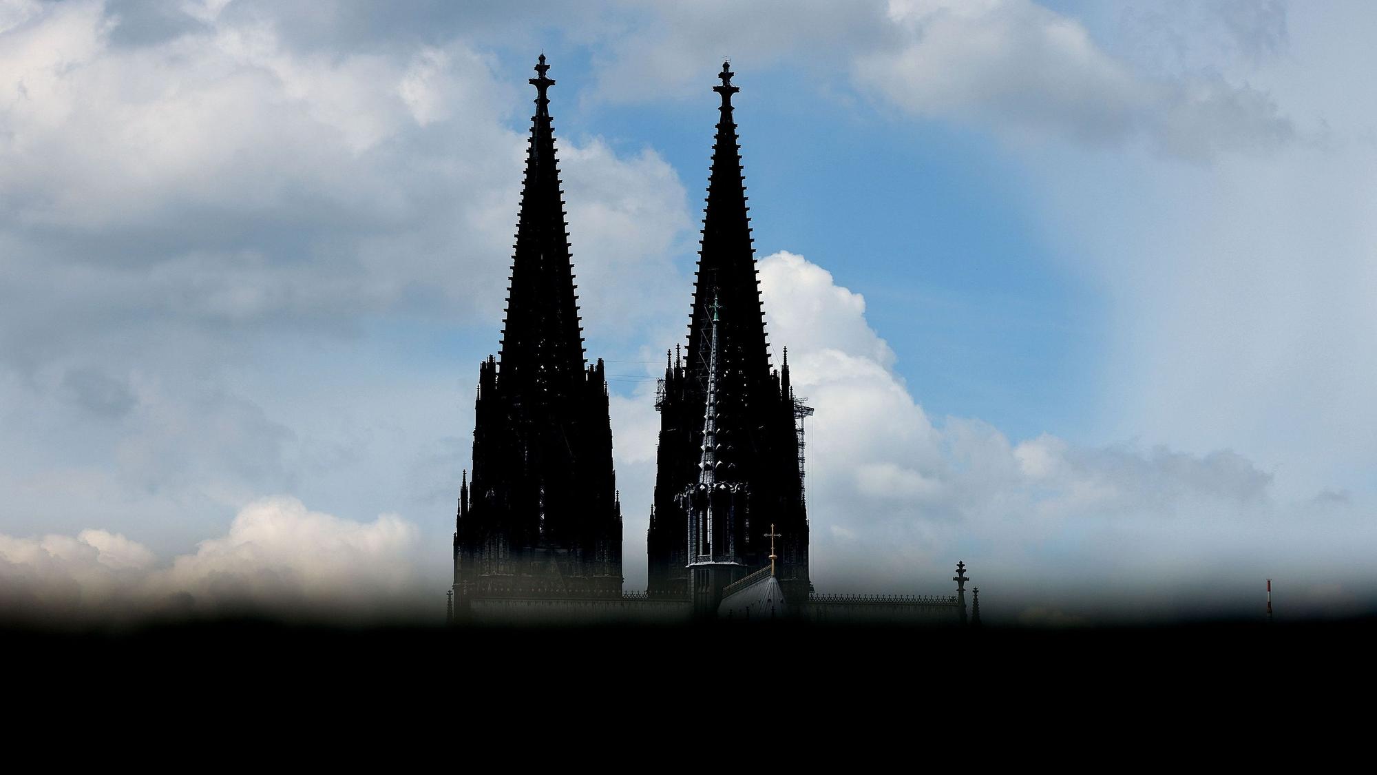 Der Kölner Dom ist hinter einer Mauer zu sehen.