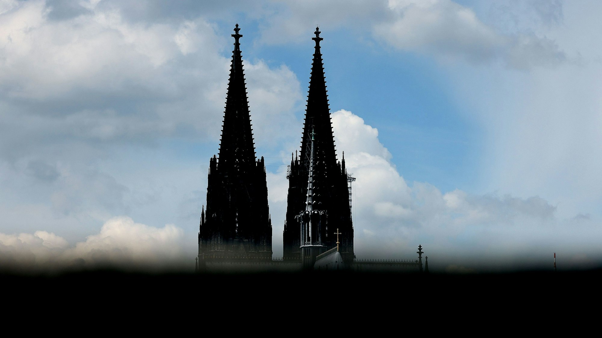 Der Kölner Dom ist hinter einer Mauer zu sehen.