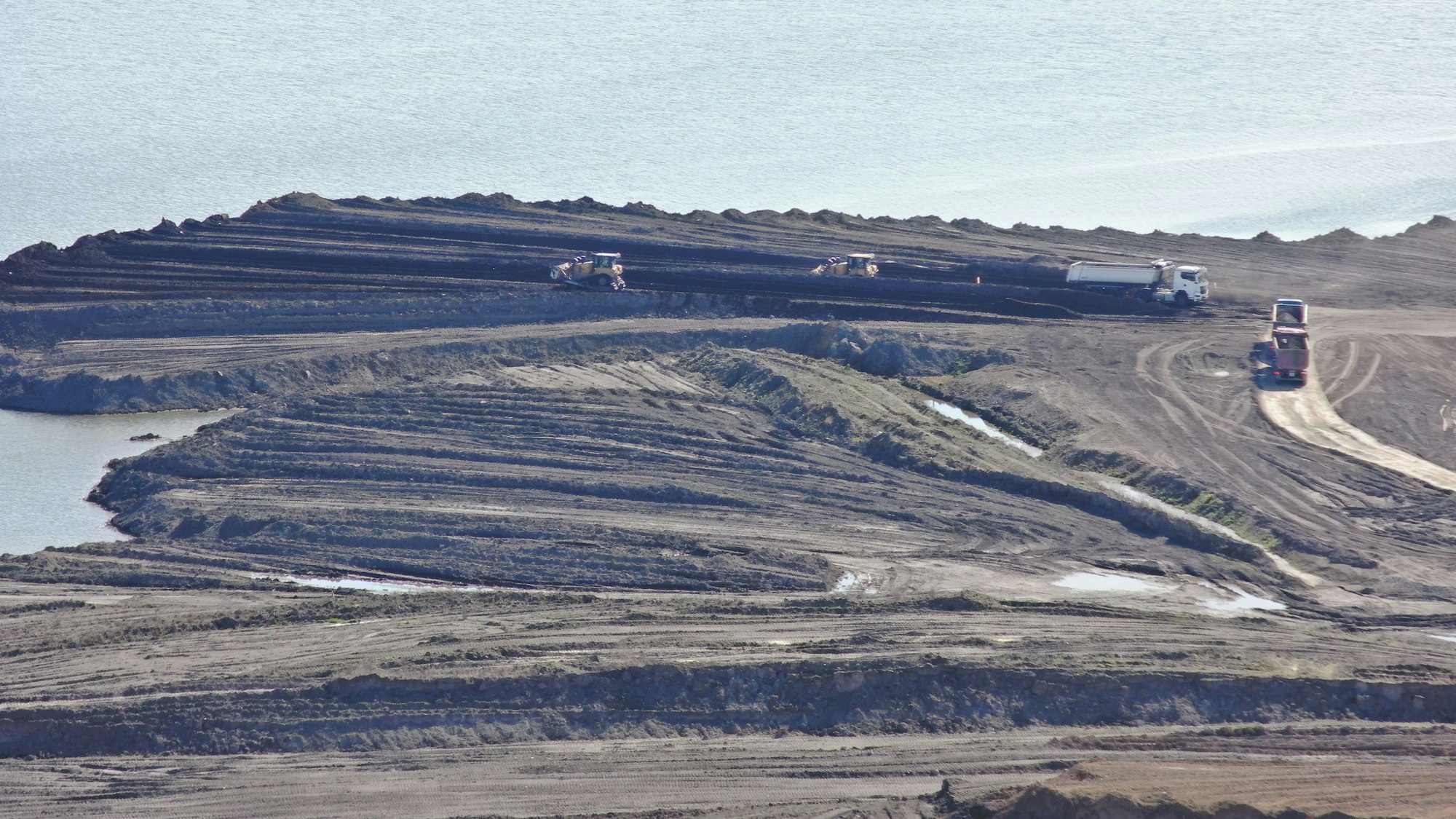 Das undatierte, mit einer Drohne aufgenommene Foto zeigt nach Polizeiangaben Arbeitsfahrzeuge, die Erde in Richtung eines Sees bewegen.