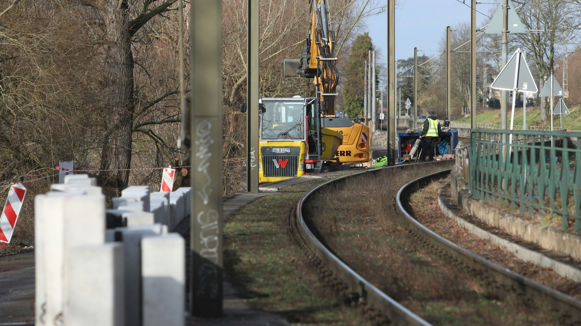 Baufahrzeuge und Betonblöcke stehen neben einer Bahntrasse.