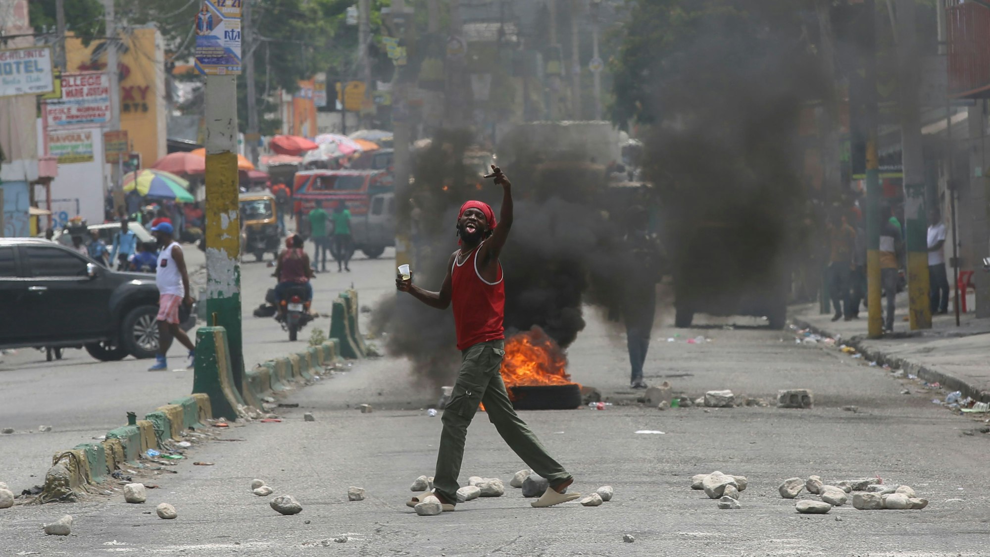 Ein Mann gestikuliert auf einer Straße, die durch brennende Reifen und Trümmer blockiert ist, während einer Demonstration, die den Rücktritt des Übergangspräsidentenrates fordert, in Port-au-Prince, Haiti.