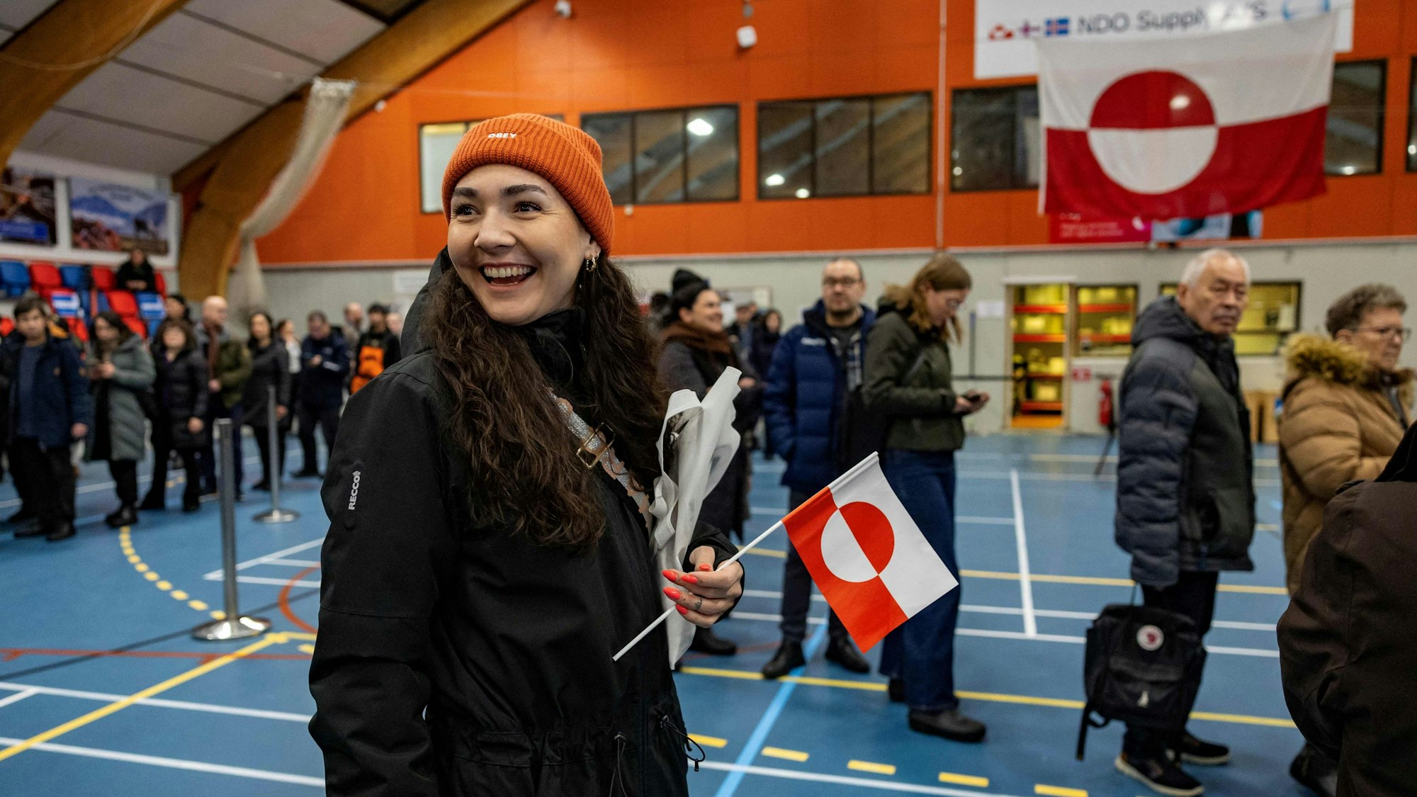 Eine Wählerin hält am Dienstag in der Schlange zur Urne eine Grönland-Flagge in der Hand.