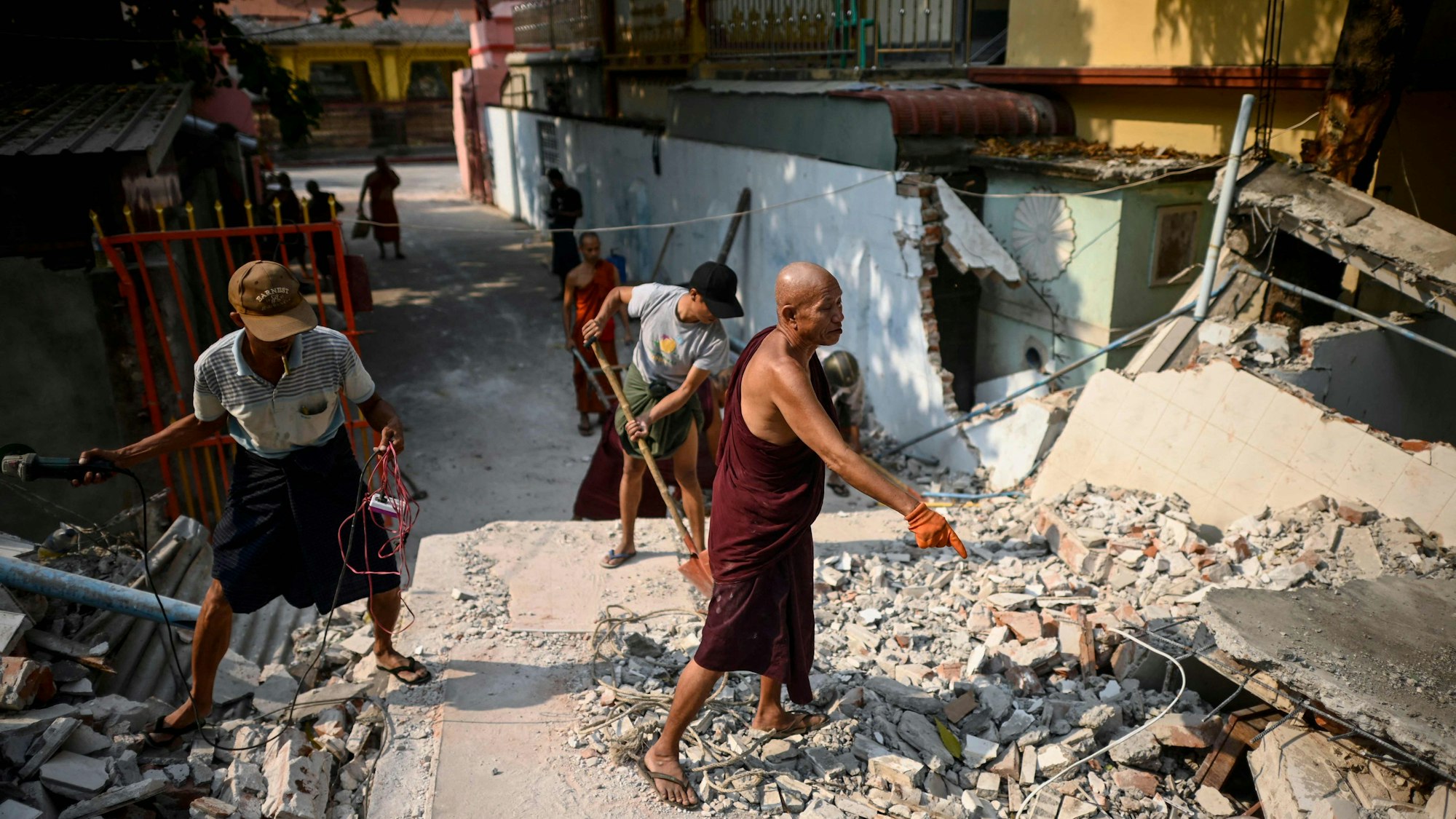 Buddhist monks clear up rubble at the damaged Thahtay Kyaung Monastery in Mandalay on April 1, 2025, four days after a major earthquake struck central Myanmar. Four days after the shallow 7.7-magnitude earthquake that killed more than 2,000 people, many people in Myanmar are still sleeping outdoors, either unable to return to ruined homes or afraid of further aftershocks. (Photo by Sai Aung MAIN / AFP)