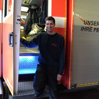 Das Foto zeigt einen jungen Mann vor einem Feuerwehrfahrzeug.