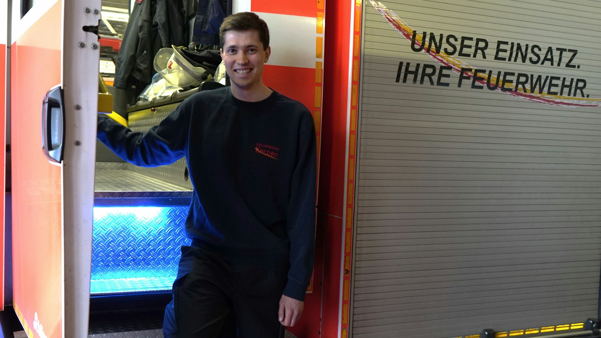 Das Foto zeigt einen jungen Mann vor einem Feuerwehrfahrzeug.