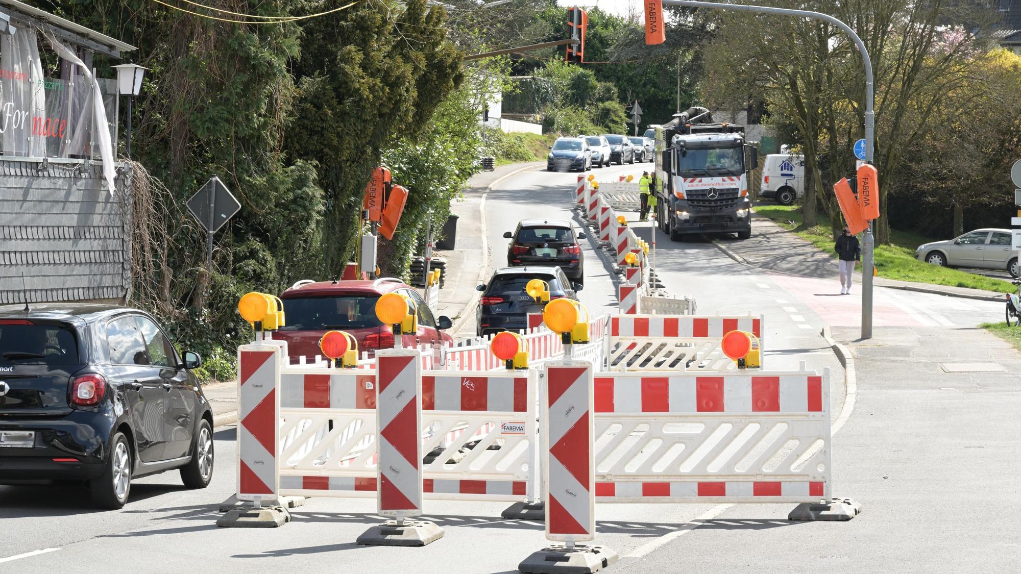 Eine Baustelle auf der Straße. Eine Fahrbahn ist mit rot-weißen Baken abgesperrt.
