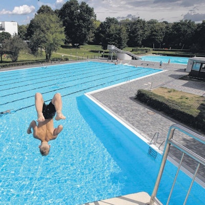 Ein Mann springt vom Sprungturm eines Freibads