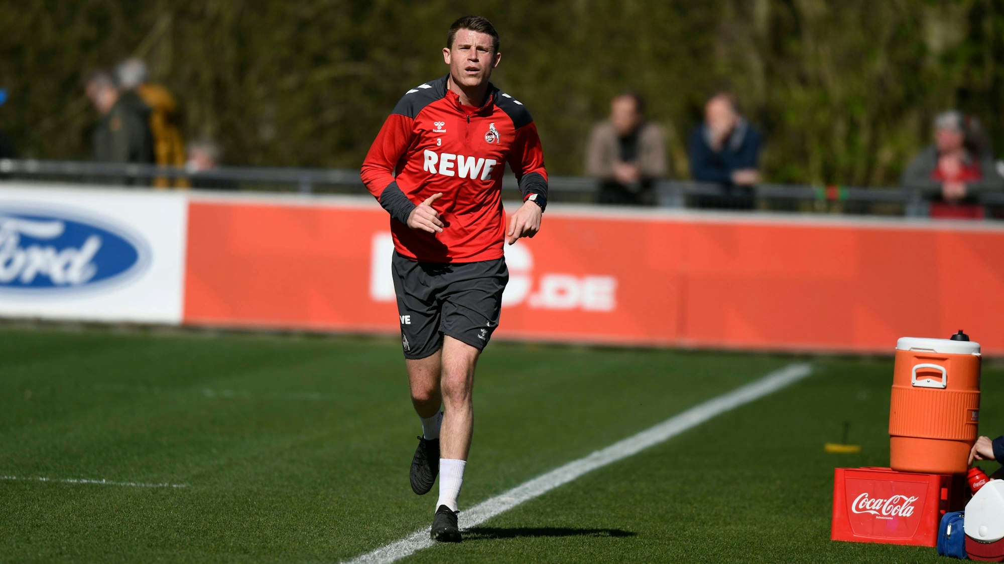 Ein Fußballspieler joggt über einen Platz.