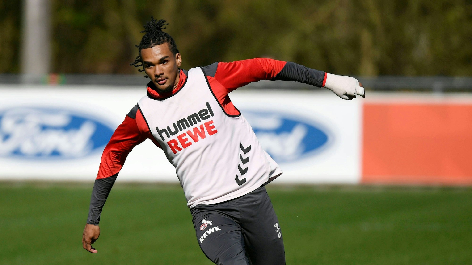 Ein Fußballspieler läuft mit einer Handmanschette über einen Trainingsplatz.