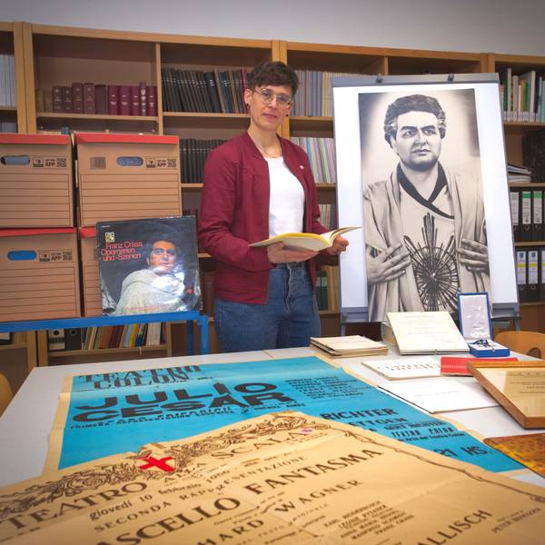 Das Foto zeigt Plakate, Urkunden und Fotos aus dem Nachlass des Opernsängers Franz Crass, dazwischen Stadtarchivarin Sarah Zeppenfeld.