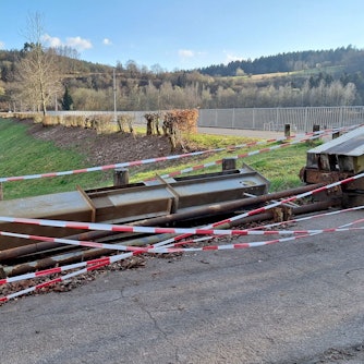 Ein Betriebsschütz der Stauanlage am Kronenburger See, das bei der Flutkatastrophe 2021 zerstört wurde, liegt am Rand des Staudamms. Der Bereich ist mit rot-weißem Flatterband abgesperrt.