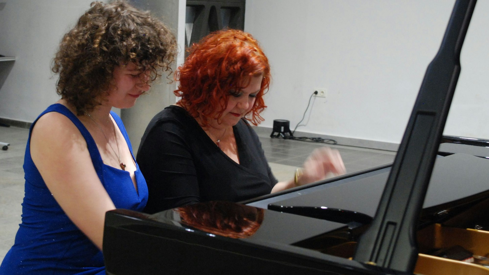 Zwei Pianistinnen sitzen an einem Konzertflügel und spielen vierhändig.