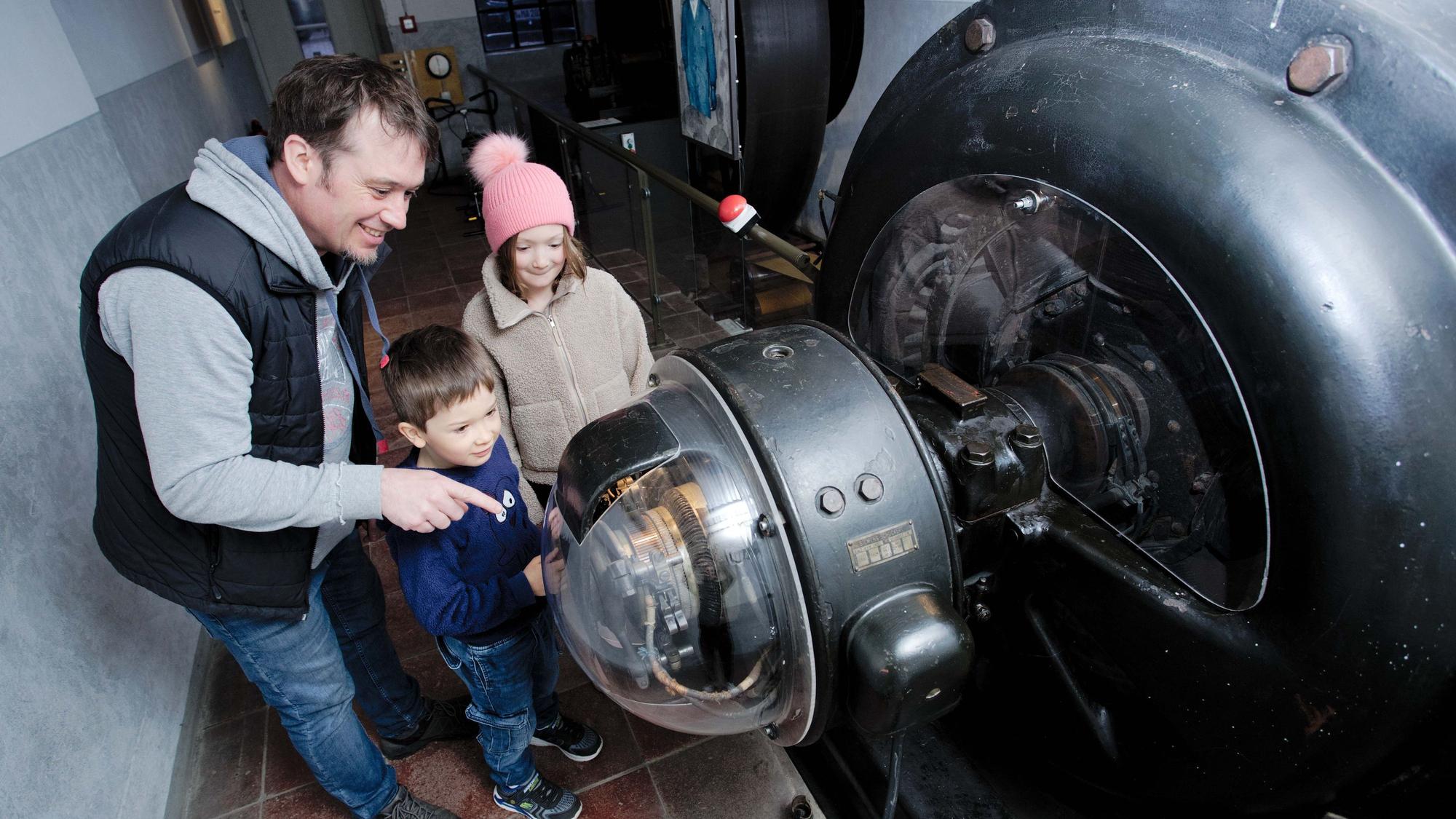 Eine Familie steht an einer alten Turbine des Industriemuseums