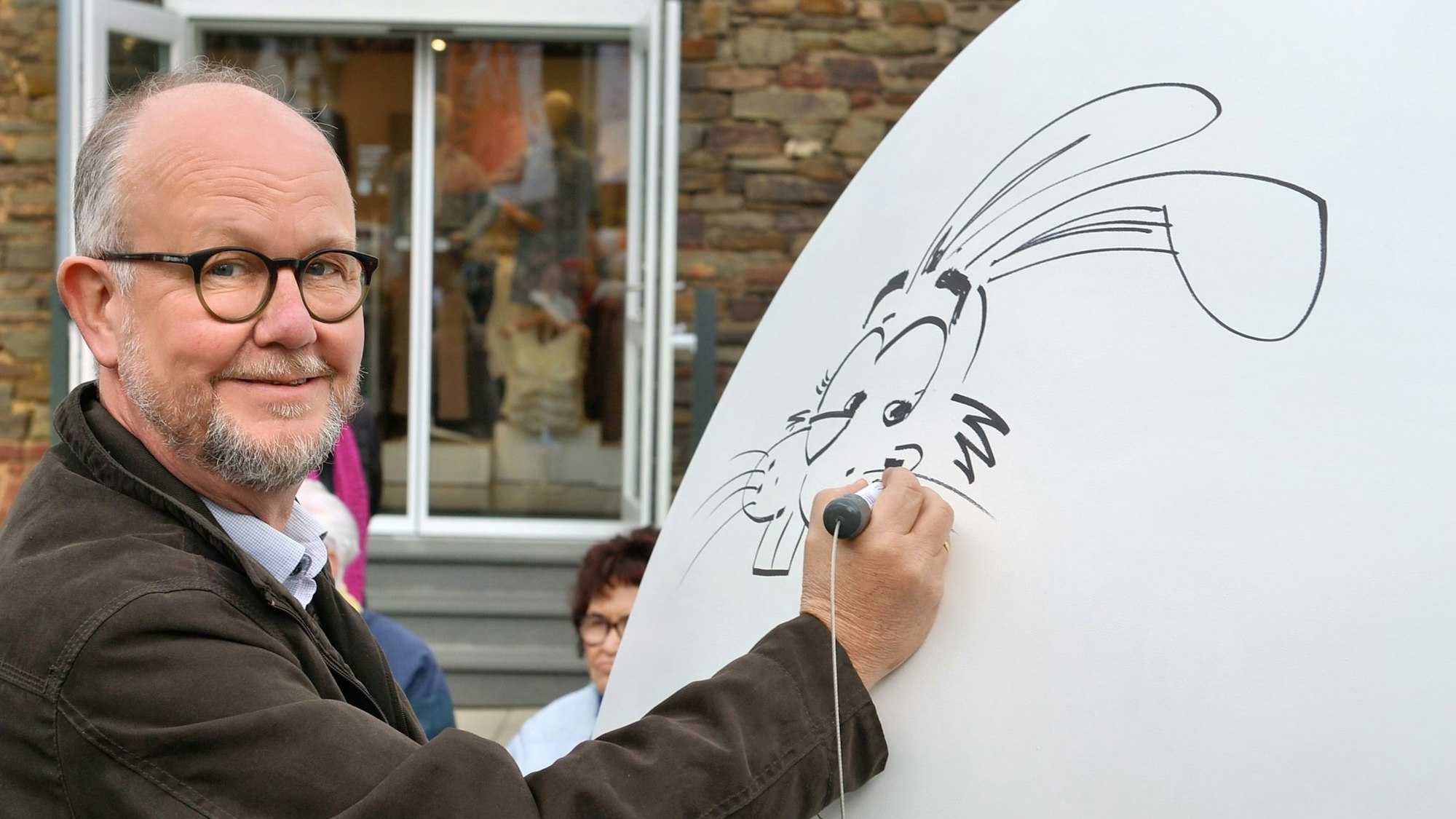 Das Bild zeigt Ralf Kramp, wie er mit einem Stift einen Hasen malt.