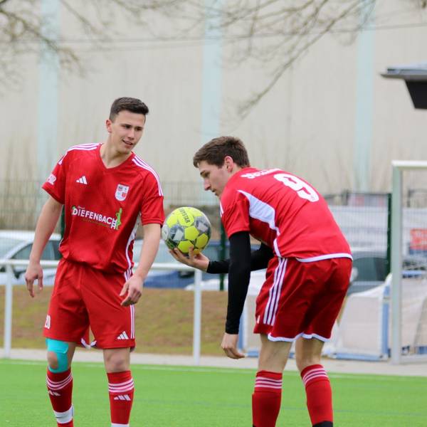 Ein Fußballer von Dahlem-Schmidtheim II hält den Ball in der Hand und legt ihn sich zum Strafstoß hin. Ein Mitspieler spricht mit ihm.