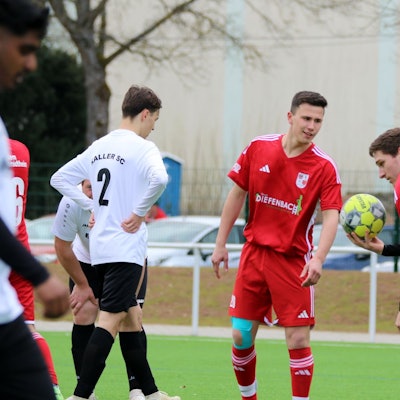 Ein Fußballer von Dahlem-Schmidtheim II hält den Ball in der Hand und legt ihn sich zum Strafstoß hin. Ein Mitspieler spricht mit ihm.