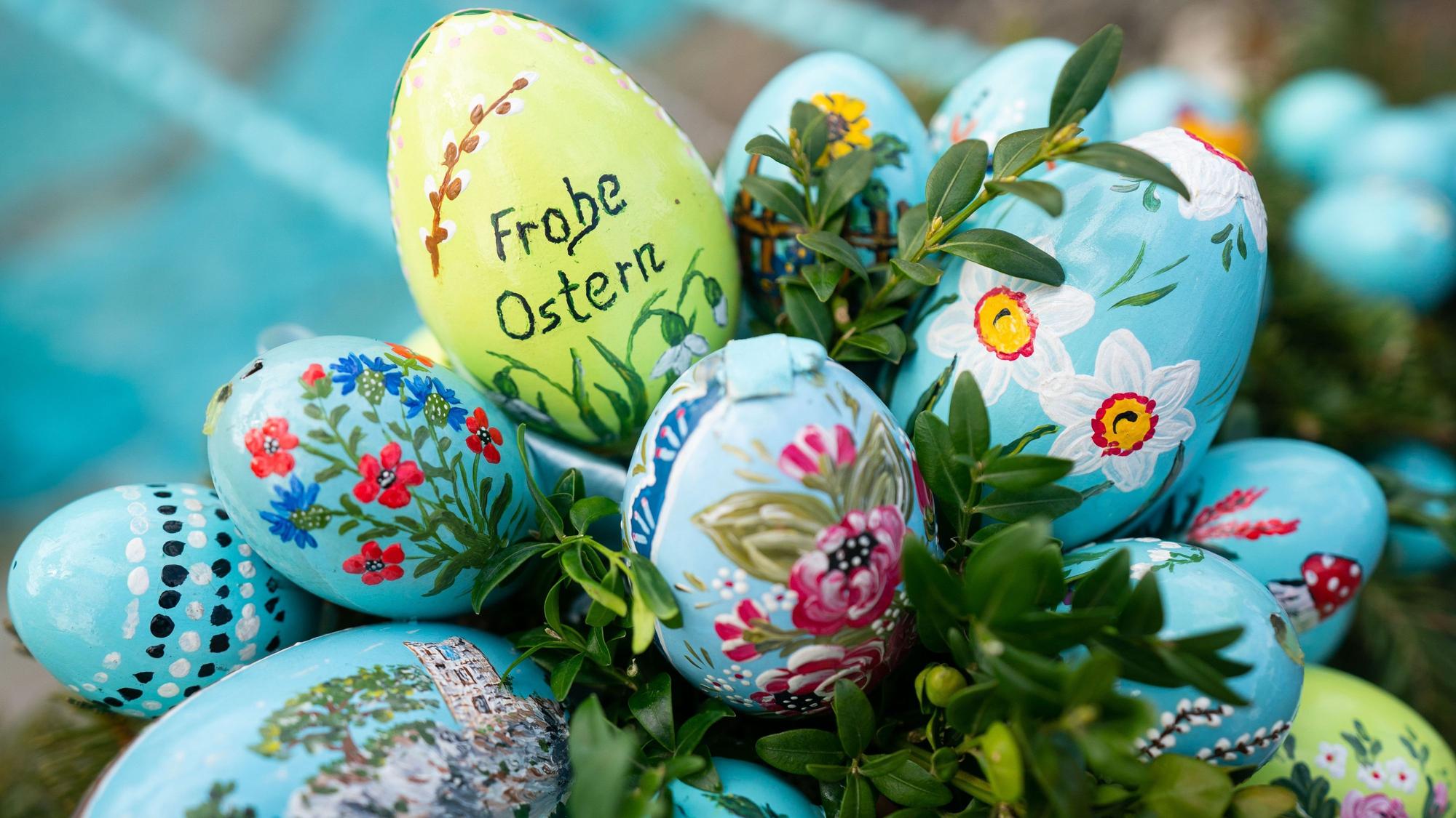 Bemalte Ostereier sind an einer Girlande an einem Osterbrunnen angebracht.
