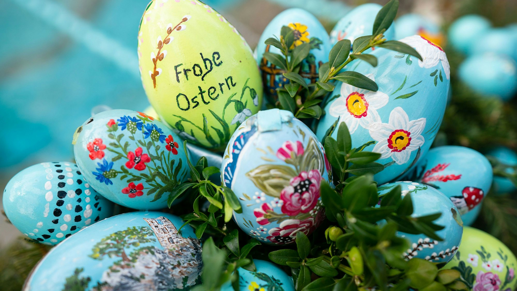 Bemalte Ostereier sind an einer Girlande an einem Osterbrunnen angebracht. (Symbolbild)