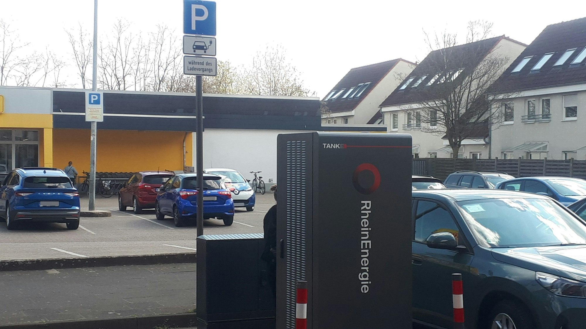 Autos stehen neben einer Elektro-Ladesäule vor einem Netto-Supermarkt.