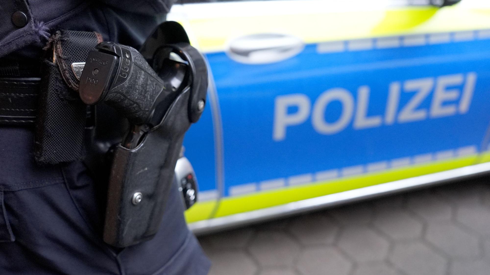 Ein Polizist steht vor einem Einsatzfahrzeug der Polizei.