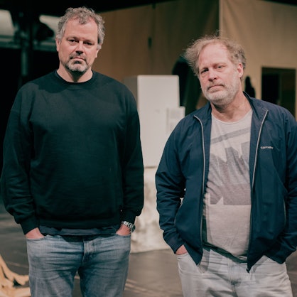 Regisseur Jan Bonny (inks) und Hauptdarsteller Ben Höppner stehen in der Halle Kalk vor den Kulissen der Inszenierung "Eisenfaust".