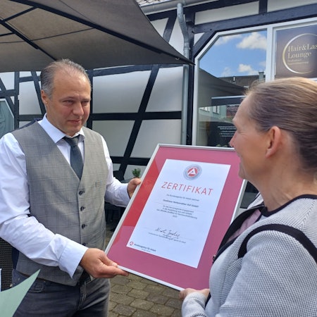 Nicole Jordy (r.) von der Agentur für Arbeit überreicht Geschäftsführer Kresimir Kozina stellvertretend für das ganze Unternehmen das Zertifikat.